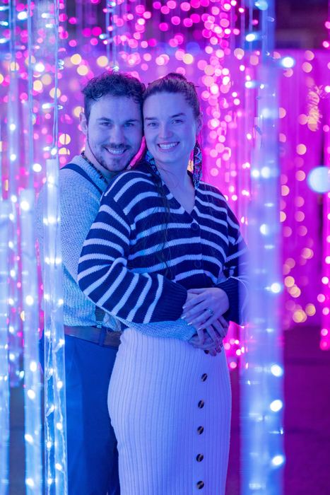 Ava and Bran hugging among pink and blue hanging lights