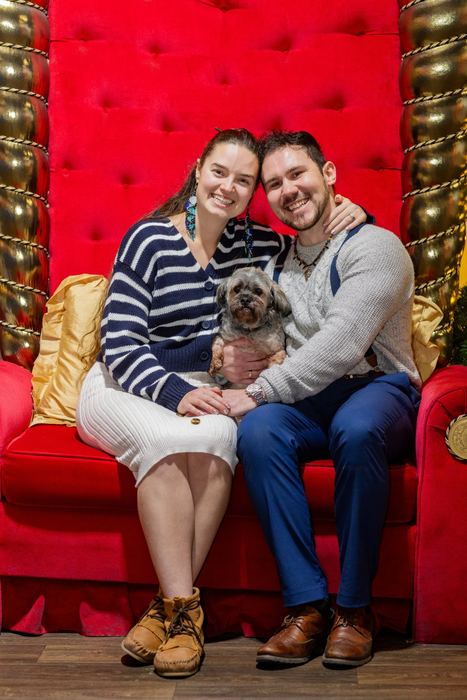 Ava and Bran on a huge red velvet chair with their dog on their laps